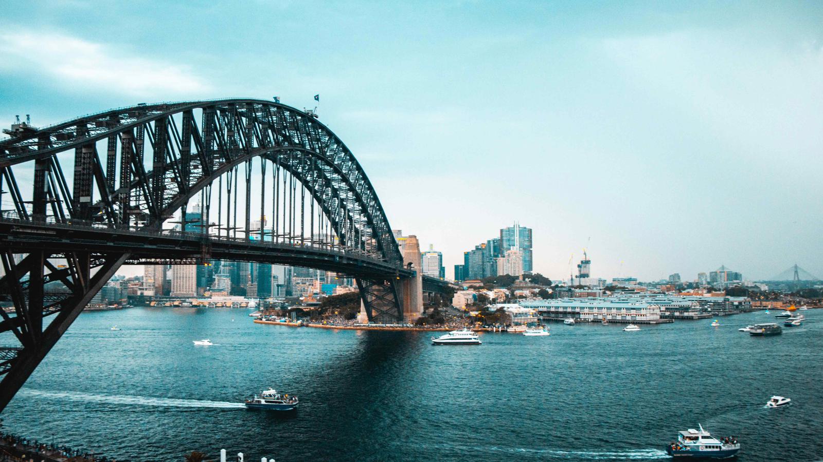 a bridge over water with boats and city in the background