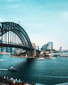 a bridge over water with boats and city in the background