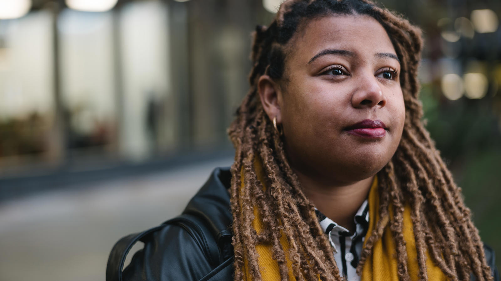 a woman with dreadlocks wearing a yellow scarf