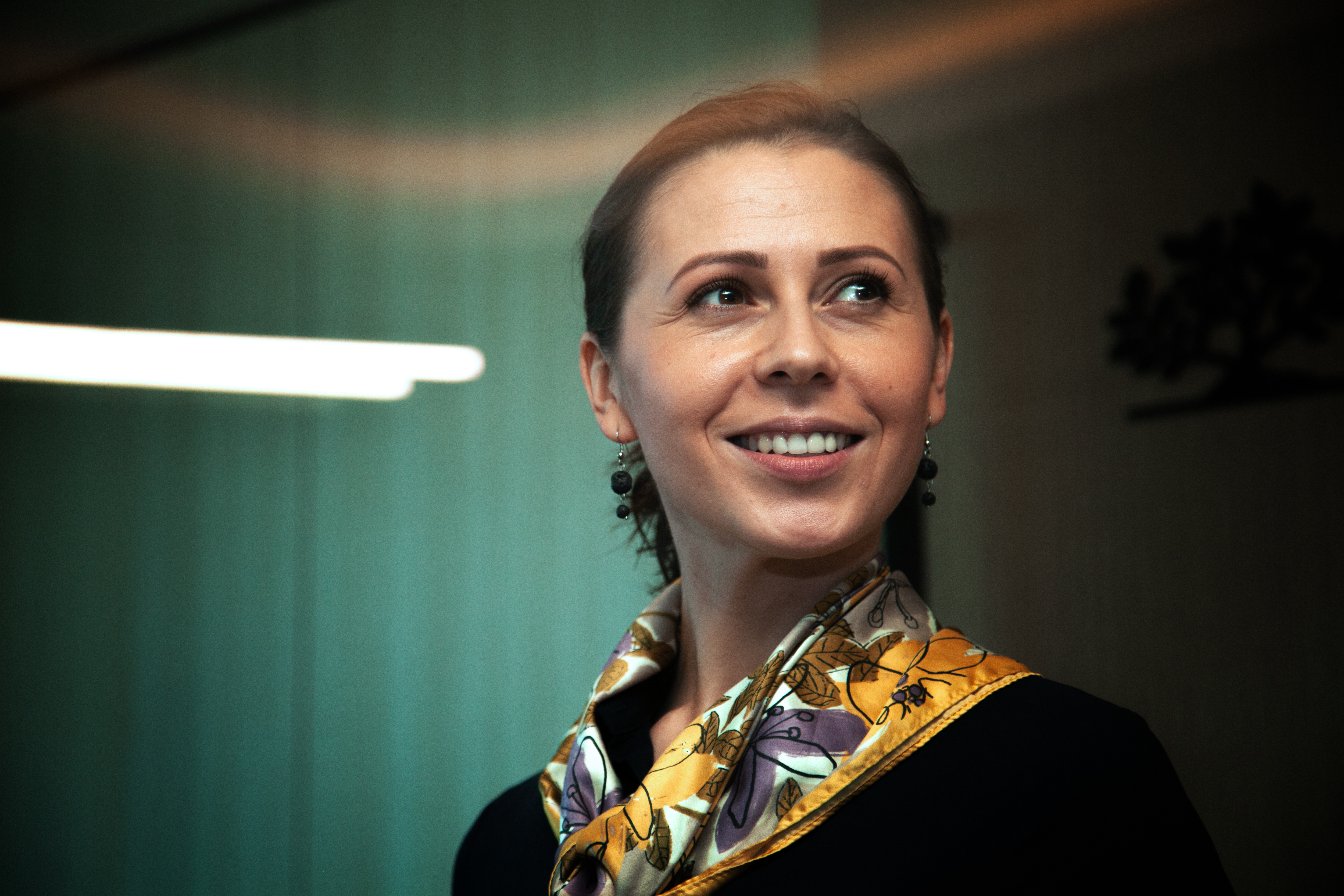 a woman smiling with a scarf around her neck
