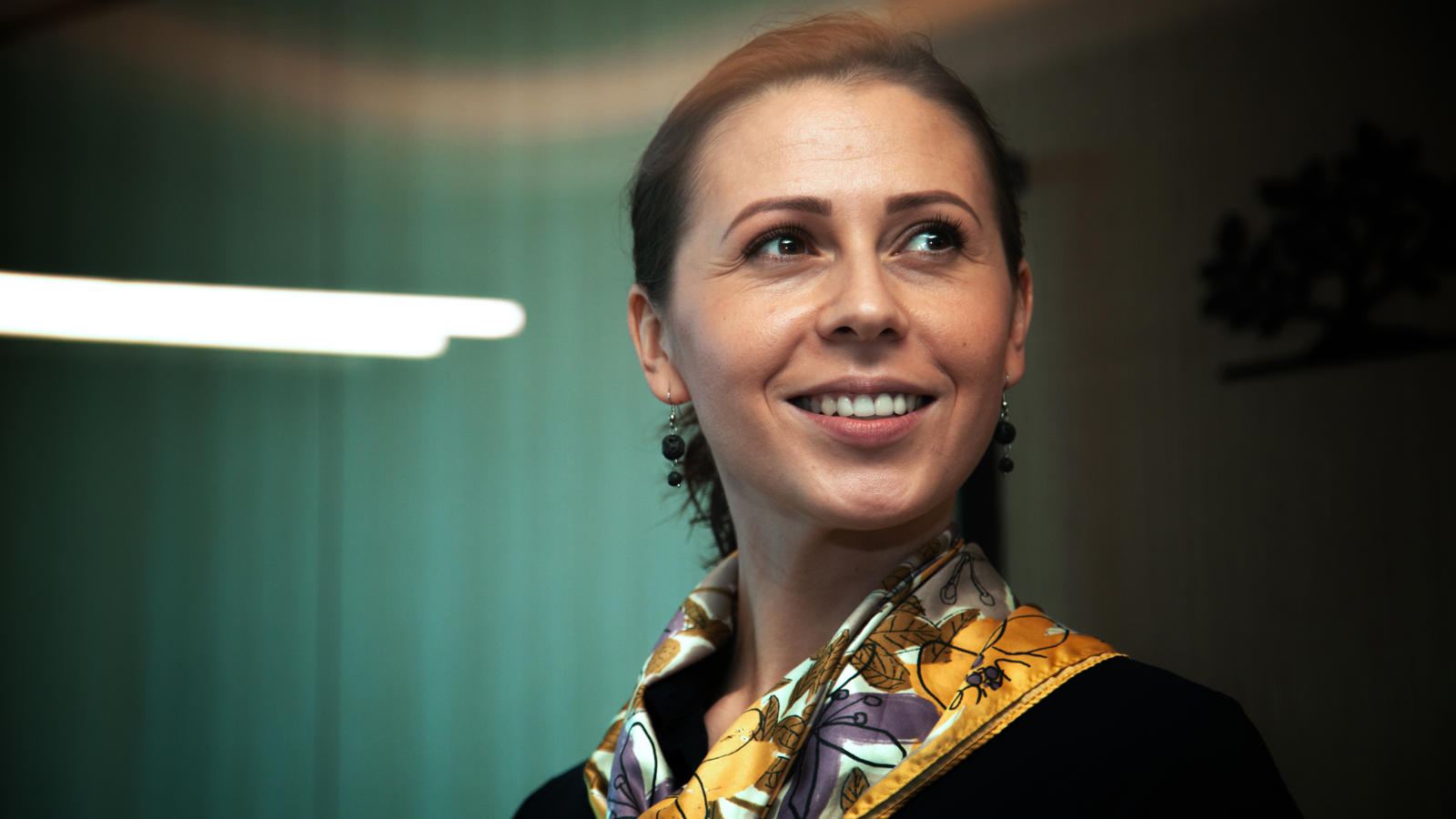 a woman smiling with a scarf around her neck