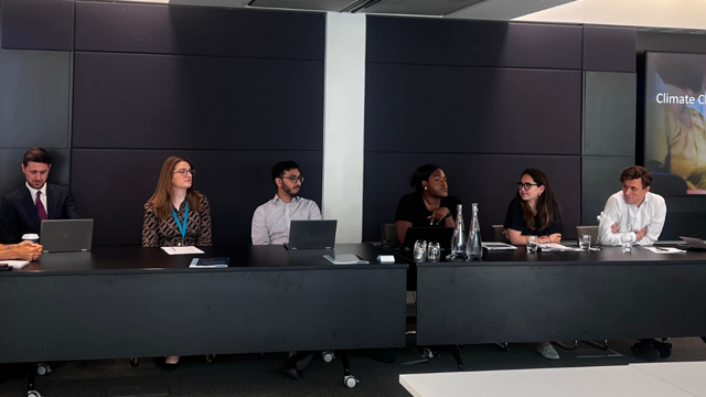 a group of people sitting at tables with laptops