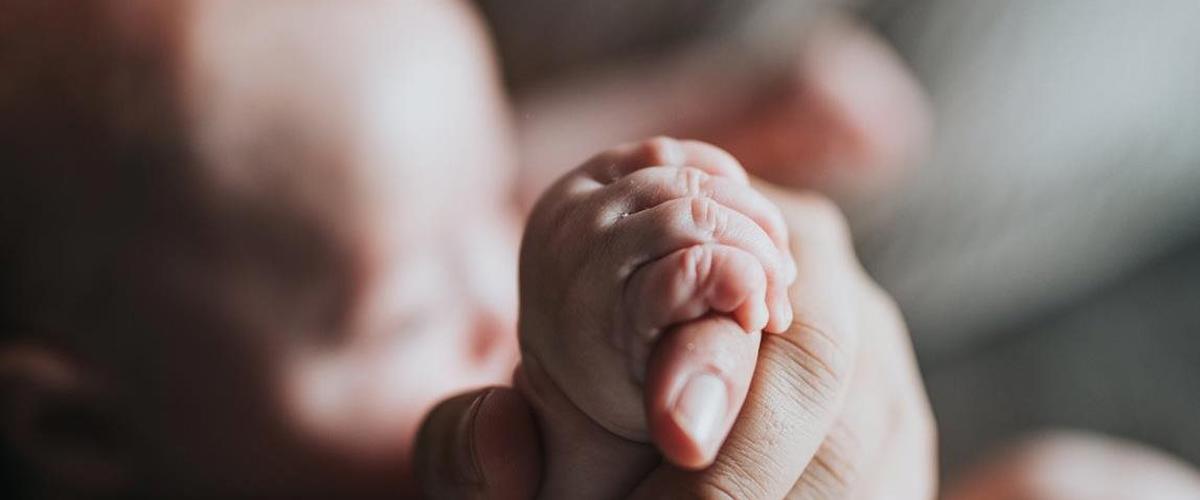 a baby's hand holding a baby's foot