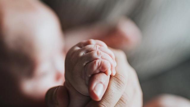 a baby's hand holding a baby's foot