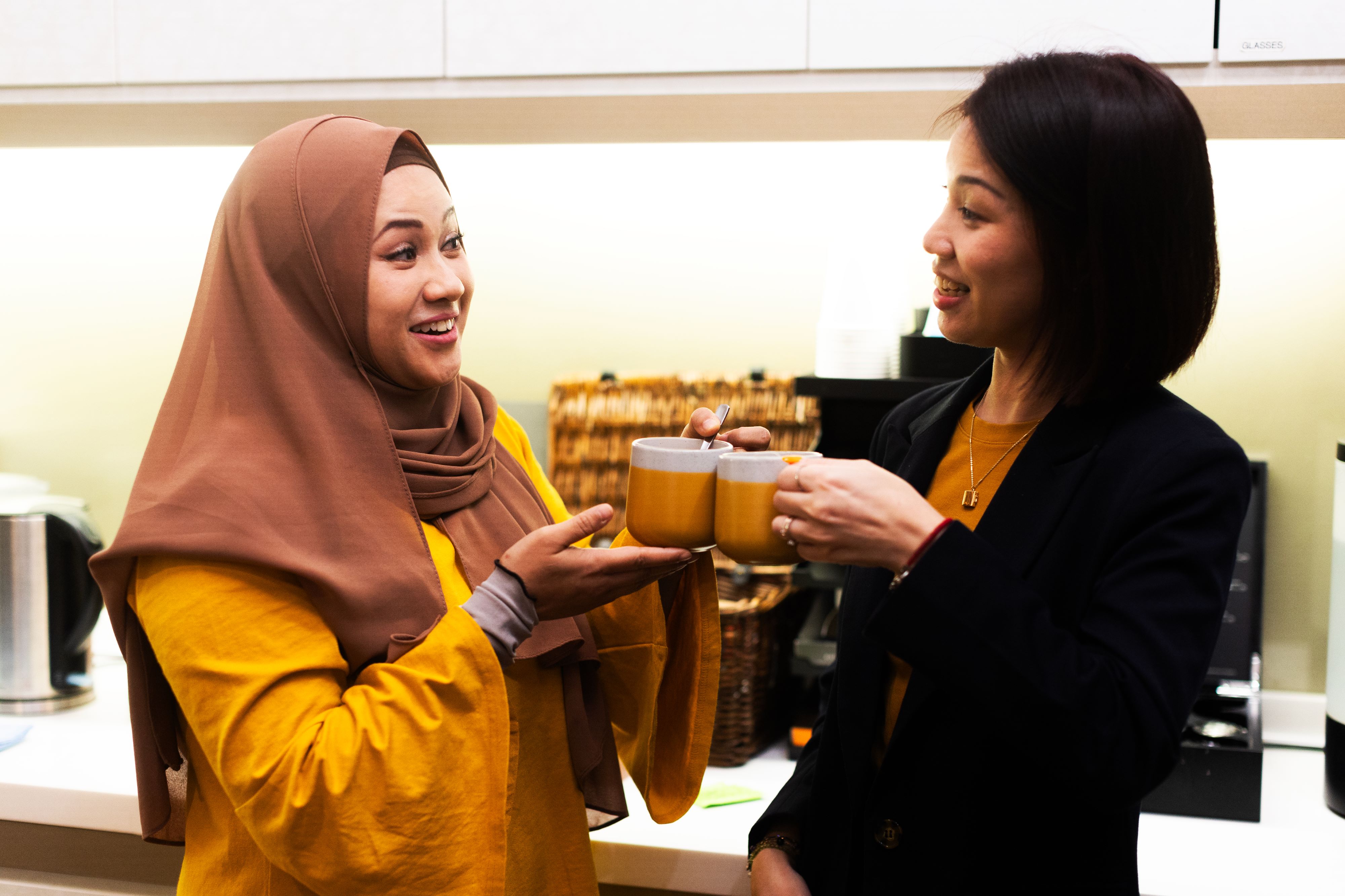 two women holding cups with coffee