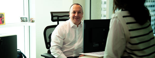 a man sitting at a desk with a woman in the background