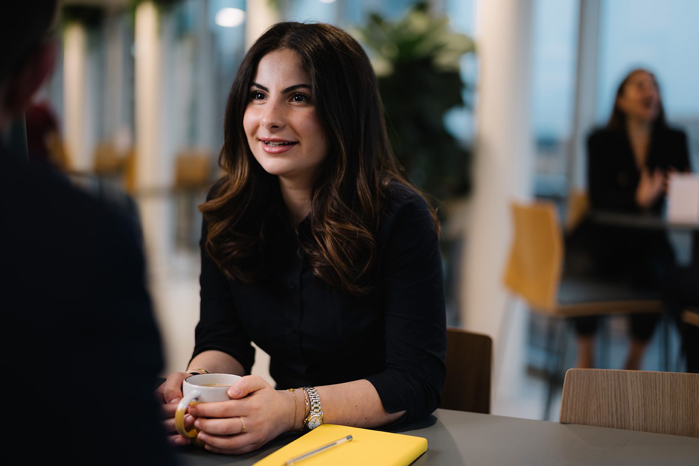 a woman sitting at a table with a cup of coffee
