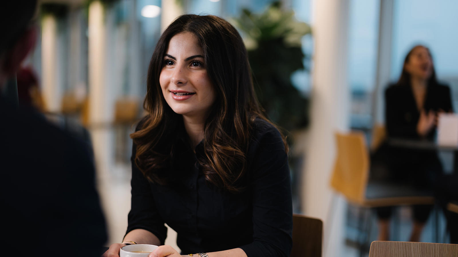 a woman sitting at a table with a cup of coffee