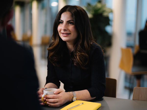a woman sitting at a table with a cup of coffee