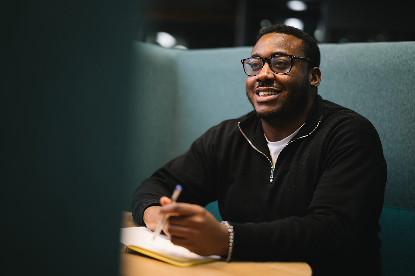 a man sitting at a table with a pen and notebook
