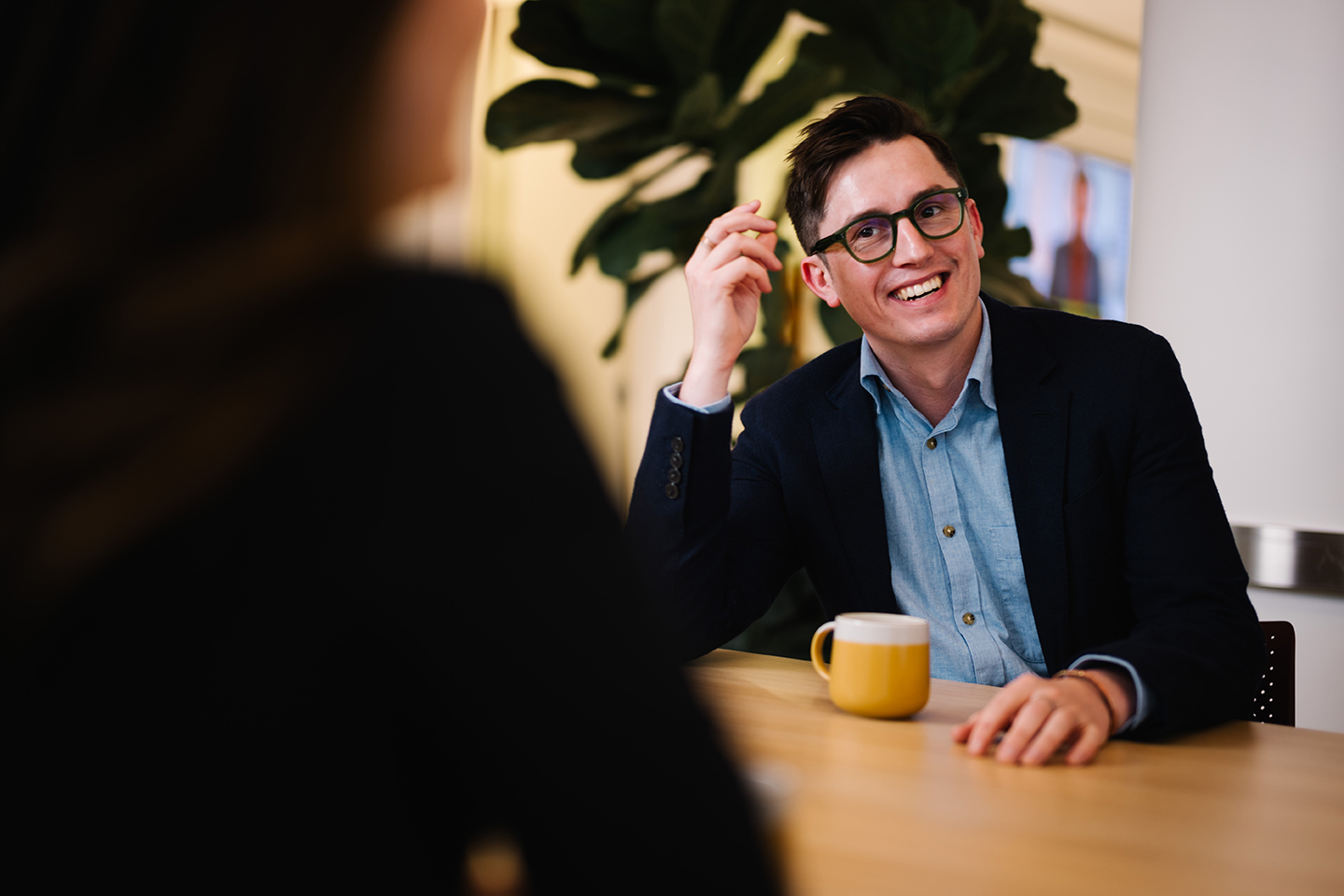 a man in a suit sitting at a table with a cup of coffee