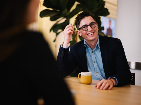 a man in a suit sitting at a table with a cup of coffee