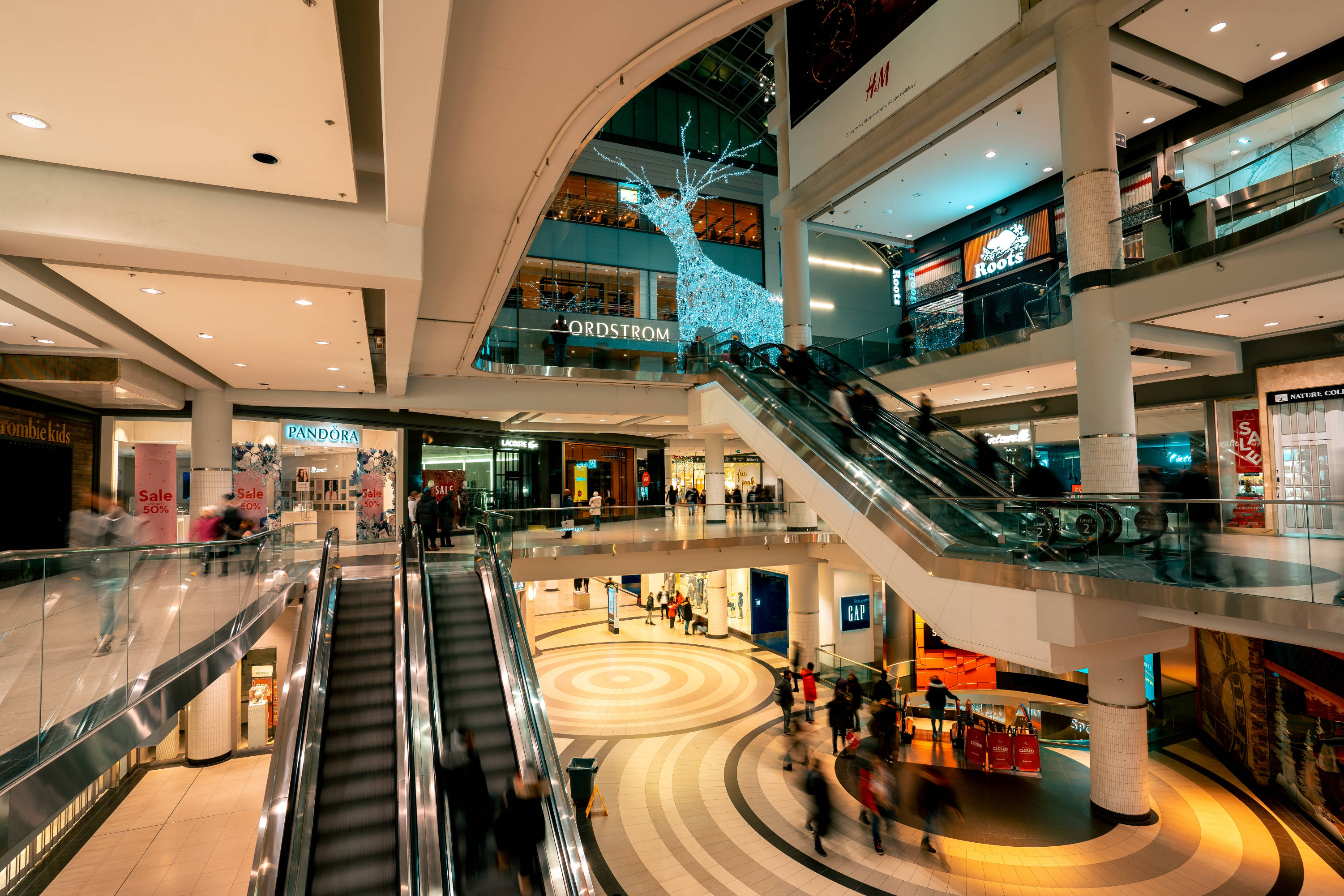 a large shopping mall with escalators and people