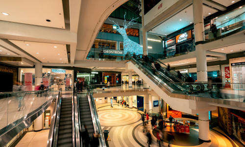 a large shopping mall with escalators and people