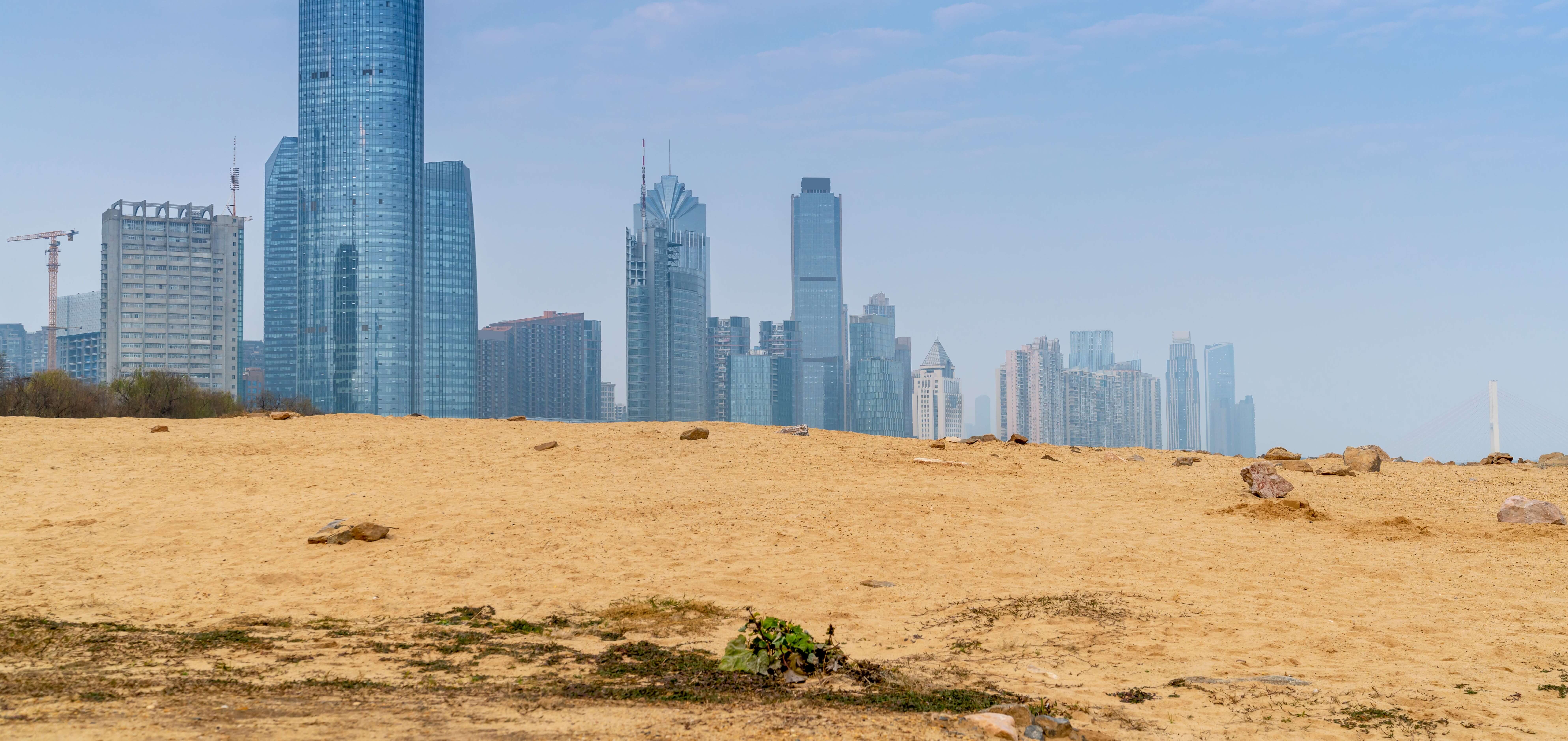 a sandy hill with a city skyline in the background