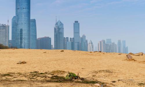 a sandy hill with a city skyline in the background