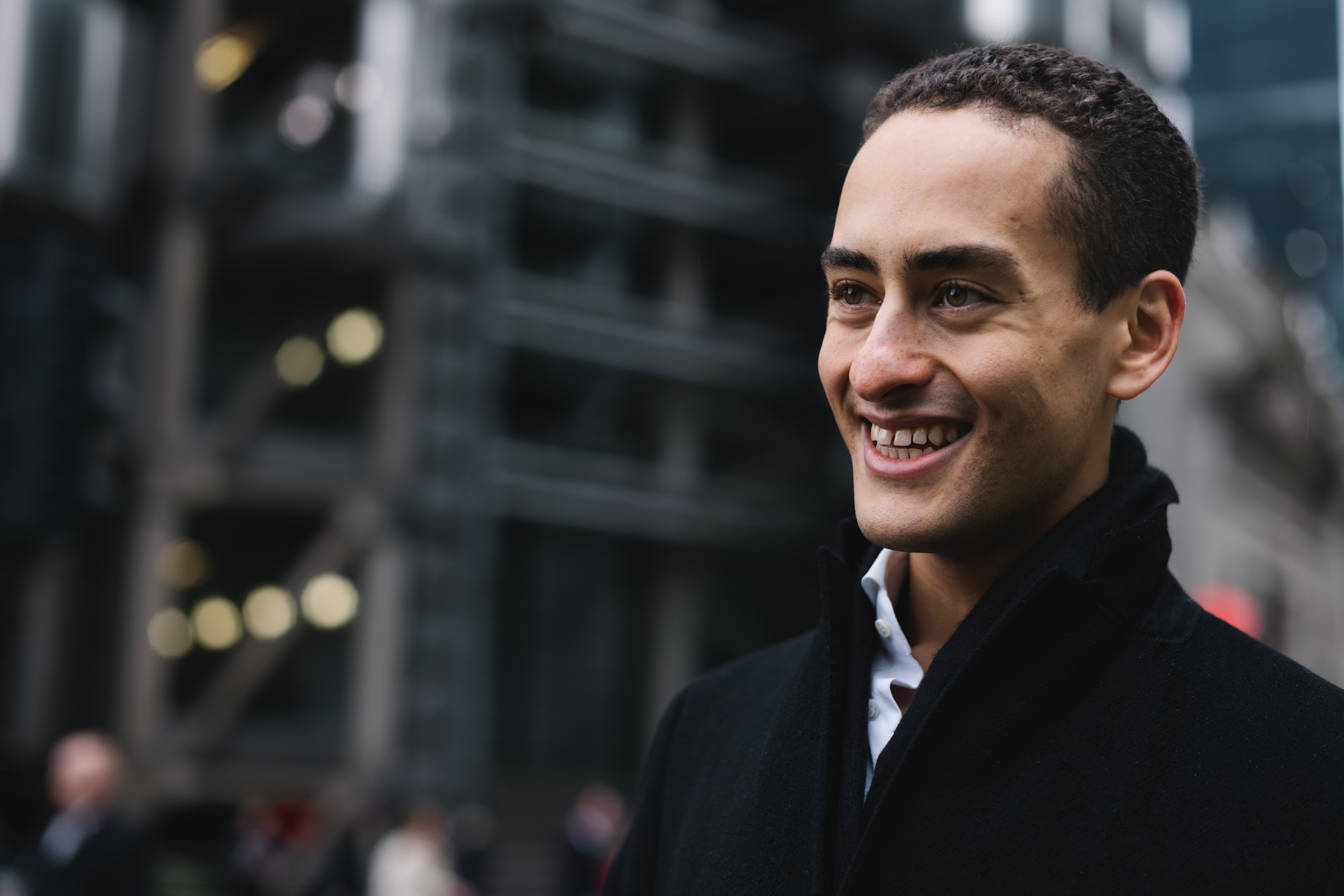 a man smiling in a black coat
