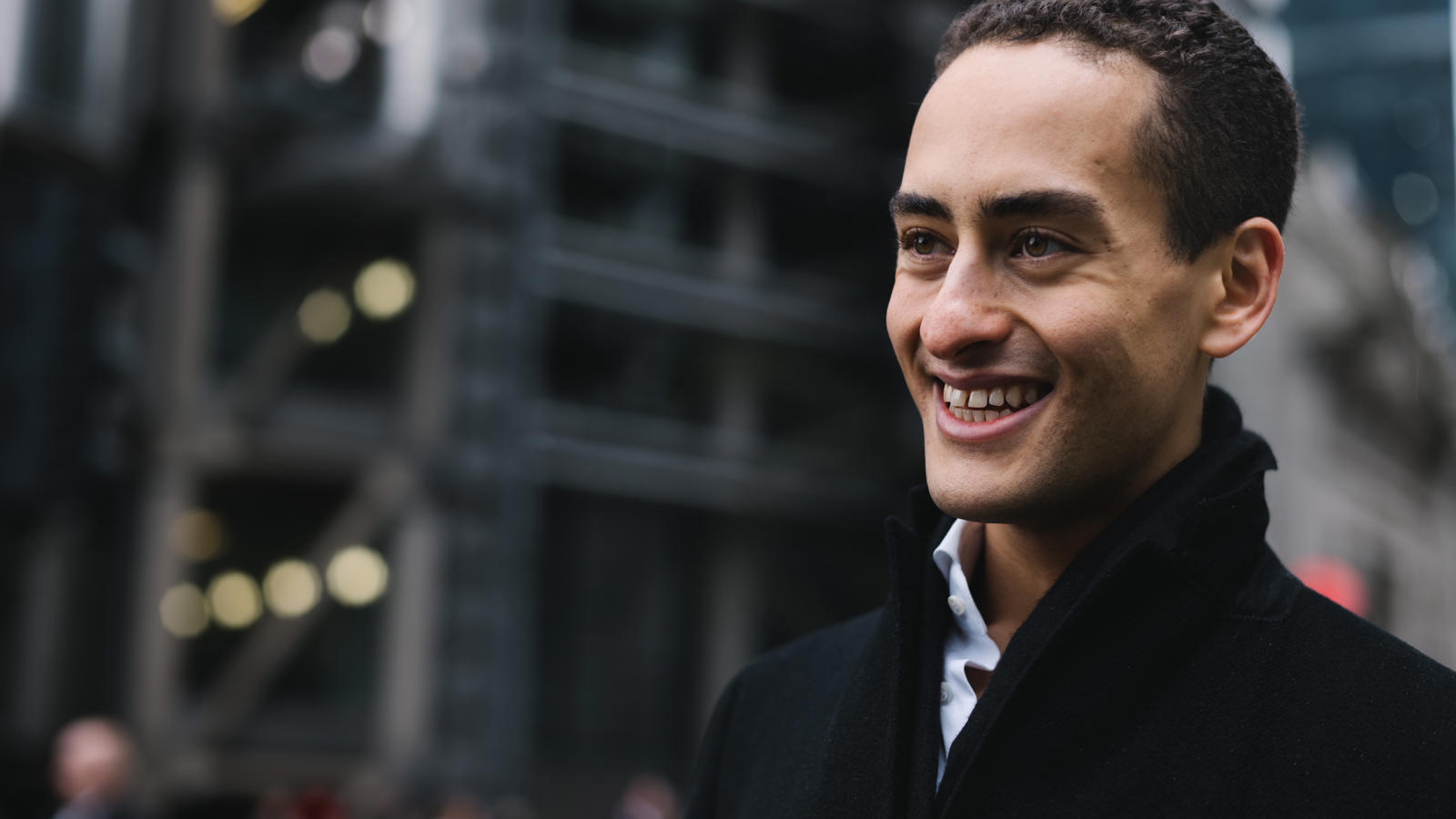 a man smiling in a black coat
