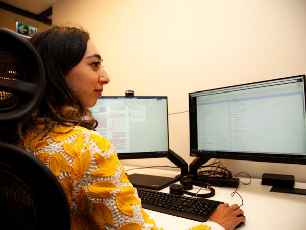 a woman sitting at a desk with two computers