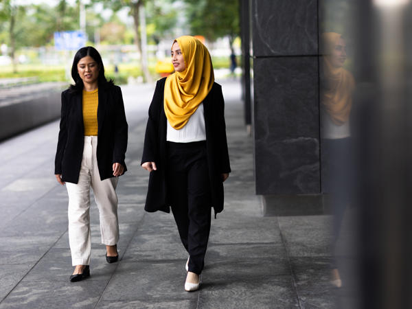 two women walking on a sidewalk