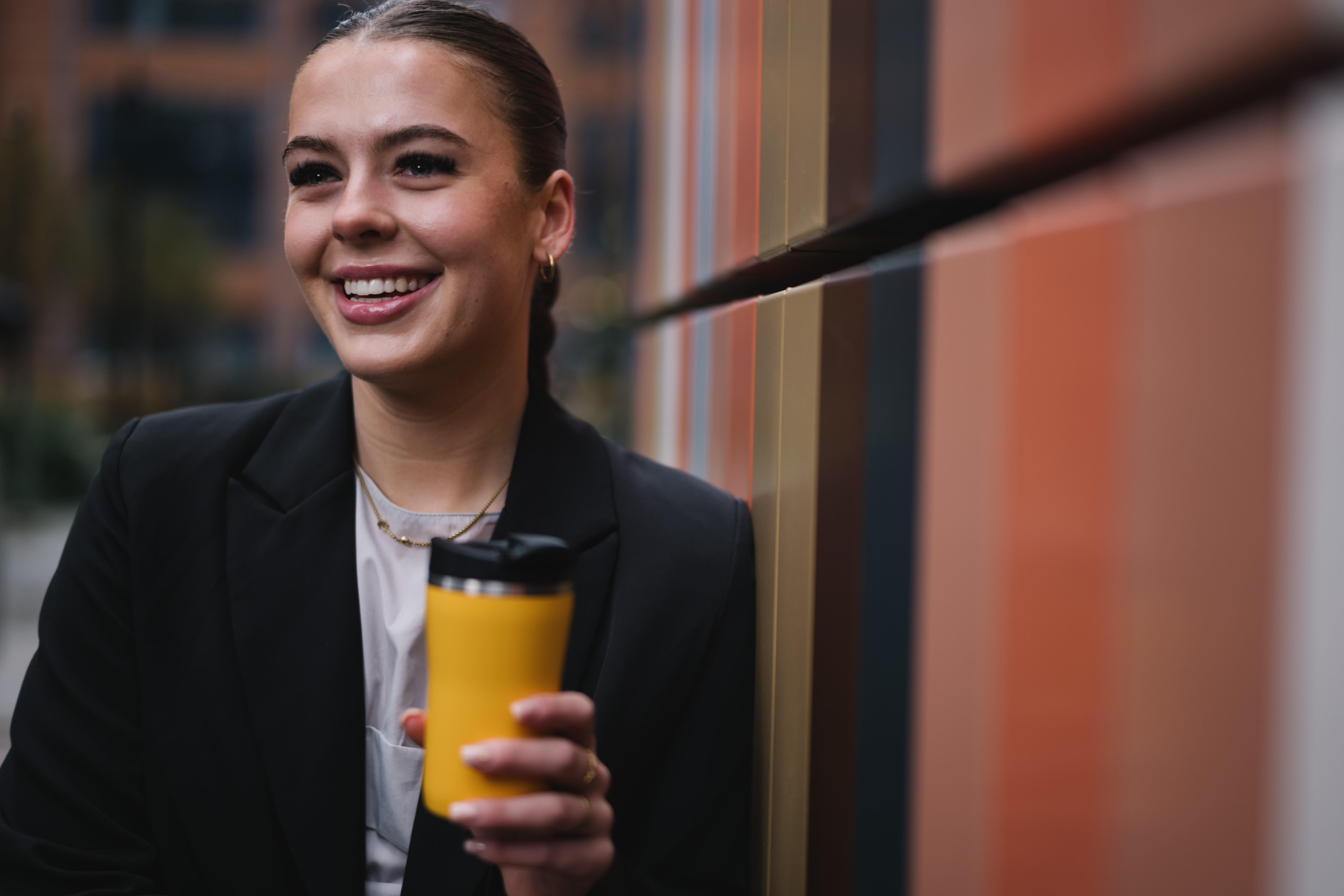 a woman smiling while holding a coffee cup