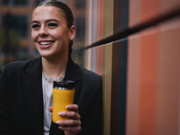 a woman smiling while holding a coffee cup